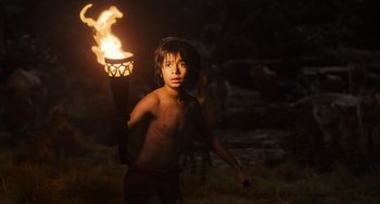 Movie still from “The Jungle Book” (2016), directed by Jon Favreau – A young boy holding a torch in the dark; Medium shot, Low angle