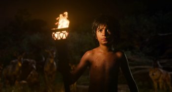 Movie still from “The Jungle Book” (2016), directed by Jon Favreau – A young boy holding a torch in the dark at night; Medium shot, Low angle
