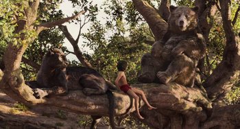 Movie still from “The Jungle Book” (2016), directed by Jon Favreau – A young boy sitting on a tree branch with two bears; Wide shot, Low angle