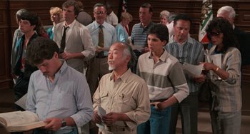 Movie still from “The Karate Kid Part II” (1986), directed by John G. Avildsen – A group of people standing in a room; Medium shot, High angle