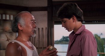 Movie still from “The Karate Kid Part II” (1986), directed by John G. Avildsen – An older man and a young boy looking at a piece of wood; Close Up shot, Over the shoulder angle