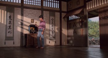 Movie still from “The Karate Kid Part II” (1986), directed by John G. Avildsen – A man standing in front of an oriental wall; Wide shot, Low angle