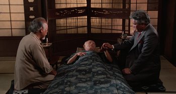 Movie still from “The Karate Kid Part II” (1986), directed by John G. Avildsen – A man laying in a bed next to two other men; Medium shot, High angle