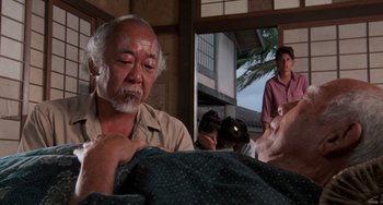 Movie still from “The Karate Kid Part II” (1986), directed by John G. Avildsen – An older man is looking down at a younger man; Medium shot, Over the shoulder angle