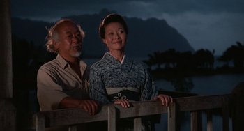 Movie still from “The Karate Kid Part II” (1986), directed by John G. Avildsen – An older man standing next to an older woman; Medium shot, Low angle