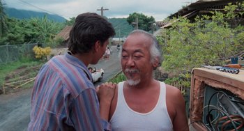 Movie still from “The Karate Kid Part II” (1986), directed by John G. Avildsen – A man is talking to another man in a white shirt; Medium shot, Over the shoulder angle