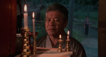 Movie still from “The Karate Kid Part II” (1986), directed by John G. Avildsen – A man sitting in front of a table with lit candles; Close Up shot, Low angle