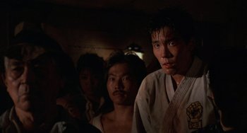 Movie still from “The Karate Kid Part II” (1986), directed by John G. Avildsen – A group of people standing next to each other in a room; Close Up shot, Low angle