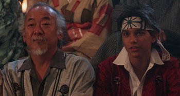 Movie still from “The Karate Kid Part II” (1986), directed by John G. Avildsen – A man and a young man sitting next to each other; Close Up shot, Over the shoulder angle