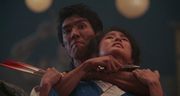 Movie still from “The Karate Kid Part II” (1986), directed by John G. Avildsen – A man and a woman holding a pair of scissors in their hands; Close Up shot, Low angle