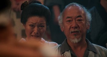 Movie still from “The Karate Kid Part II” (1986), directed by John G. Avildsen – An older man and a younger woman looking at the camera; Close Up shot, Low angle