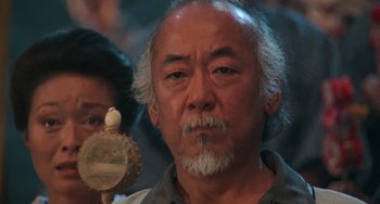 Movie still from “The Karate Kid Part II” (1986), directed by John G. Avildsen – An older man with a bird on his shoulder; Close Up shot, Low angle