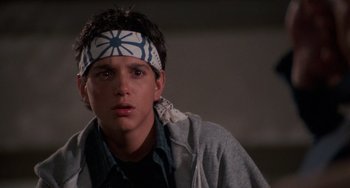 Movie still from “The Karate Kid Part III” (1989), directed by John G. Avildsen – A young man wearing a head band in a dark room; Close Up shot, Low angle