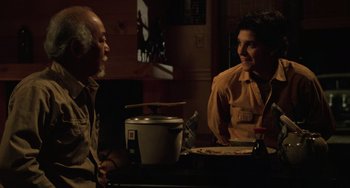 Movie still from “The Karate Kid Part III” (1989), directed by John G. Avildsen – Two people are sitting at a table talking to each other; Medium shot, Over the shoulder angle