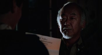 Movie still from “The Karate Kid Part III” (1989), directed by John G. Avildsen – An older man is holding a piece of paper; Close Up shot, Over the shoulder angle