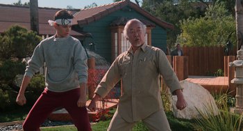 Movie still from “The Karate Kid Part III” (1989), directed by John G. Avildsen – An older man and a young boy are playing a game; Wide shot, Low angle