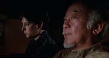 Movie still from “The Karate Kid Part III” (1989), directed by John G. Avildsen – A man and a young boy looking at the camera; Close Up shot, Low angle