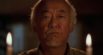 Movie still from “The Karate Kid Part III” (1989), directed by John G. Avildsen – An older man with a gray beard looking at the camera; Close Up shot, Low angle
