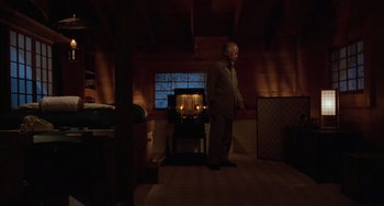 Movie still from “The Karate Kid Part III” (1989), directed by John G. Avildsen – An older man standing in a room with a fireplace; Wide shot, Low angle