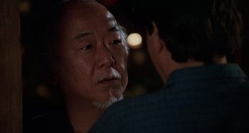 Movie still from “The Karate Kid Part III” (1989), directed by John G. Avildsen – An older man and a younger man are talking to each other; Close Up shot, Over the shoulder angle