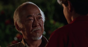 Movie still from “The Karate Kid Part III” (1989), directed by John G. Avildsen – An older man with a beard is looking into the distance; Close Up shot, Over the shoulder angle