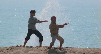 Movie still from “The Karate Kid Part III” (1989), directed by John G. Avildsen – A man and a woman are practicing martial arts on the beach; Wide shot, Low angle