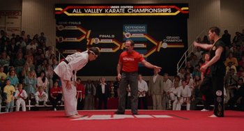 Movie still from “The Karate Kid Part III” (1989), directed by John G. Avildsen – Two men are practicing martial arts in front of an audience; Wide shot, Low angle