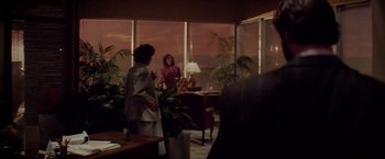 Movie still from “Die Hard” (1988), directed by John McTiernan – Two women are sitting in front of a large window; Wide shot, Over the shoulder angle