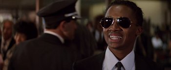 Movie still from “Die Hard” (1988), directed by John McTiernan – A person wearing a suit and sunglasses; Close Up shot, Low angle