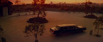 Movie still from “Die Hard” (1988), directed by John McTiernan – A limo is driving down the street at sunset; Extreme Wide shot, High angle
