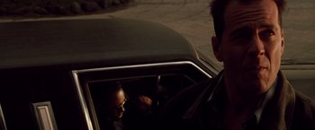 Movie still from “Die Hard” (1988), directed by John McTiernan – A man sitting in the back seat of a car; Close Up shot, Over the shoulder angle