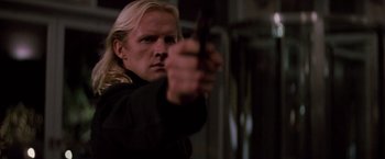 Movie still from “Die Hard” (1988), directed by John McTiernan – A man holding a gun in his right hand; Close Up shot, Low angle