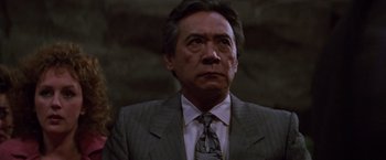 Movie still from “Die Hard” (1988), directed by John McTiernan – A man in a suit and tie looking up; Close Up shot, Low angle