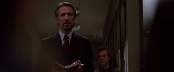 Movie still from “Die Hard” (1988), directed by John McTiernan – A man in a suit and tie holding a book; Close Up shot, Low angle