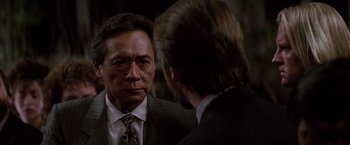 Movie still from “Die Hard” (1988), directed by John McTiernan – A man in a business suit talking to another man in a business suit; Close Up shot, Over the shoulder angle