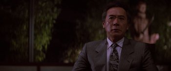 Movie still from “Die Hard” (1988), directed by John McTiernan – An older man in a suit and tie looking into the distance; Close Up shot, Low angle