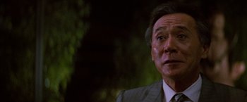 Movie still from “Die Hard” (1988), directed by John McTiernan – An older man wearing a suit and tie looking at the camera; Close Up shot, Low angle