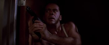 Movie still from “Die Hard” (1988), directed by John McTiernan – A man holding a gun in a dark room; Close Up shot, Low angle