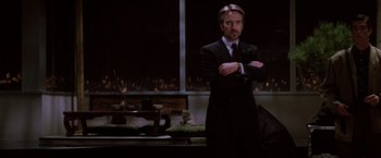 Movie still from “Die Hard” (1988), directed by John McTiernan – A man in a suit and tie standing in front of a window; Medium shot, Low angle