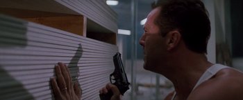 Movie still from “Die Hard” (1988), directed by John McTiernan – A man holding a gun up to his face; Close Up shot, Low angle