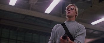 Movie still from “Die Hard” (1988), directed by John McTiernan – A man holding a camera in a warehouse; Medium shot, Low angle