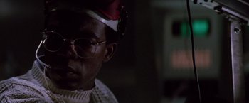 Movie still from “Die Hard” (1988), directed by John McTiernan – A person wearing glasses and a hat; Close Up shot, Low angle