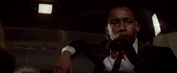 Movie still from “Die Hard” (1988), directed by John McTiernan – A man in a suit and tie holding a guitar; Close Up shot, Low angle