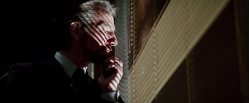 Movie still from “Die Hard” (1988), directed by John McTiernan – A man in a suit looking out of a window; Close Up shot, Low angle