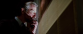 Movie still from “Die Hard” (1988), directed by John McTiernan – A man talking on a cell phone near a window; Close Up shot, Low angle