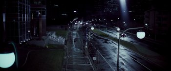 Movie still from “Die Hard” (1988), directed by John McTiernan – A city street at night lit by street lights; Extreme Wide shot, High angle