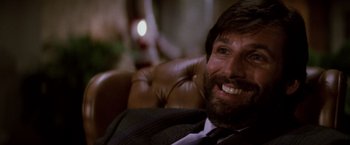 Movie still from “Die Hard” (1988), directed by John McTiernan – A person wearing a suit and smiling; Close Up shot, Low angle