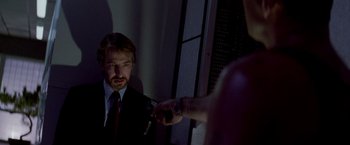 Movie still from “Die Hard” (1988), directed by John McTiernan – A man in a suit and tie holding a cigarette; Close Up shot, Over the shoulder angle