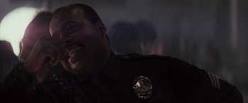 Movie still from “Die Hard” (1988), directed by John McTiernan – A man in a police uniform is laughing; Close Up shot, Low angle