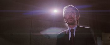 Movie still from “Die Hard” (1988), directed by John McTiernan – A man wearing a suit and tie looking up at the sun; Close Up shot, Low angle
